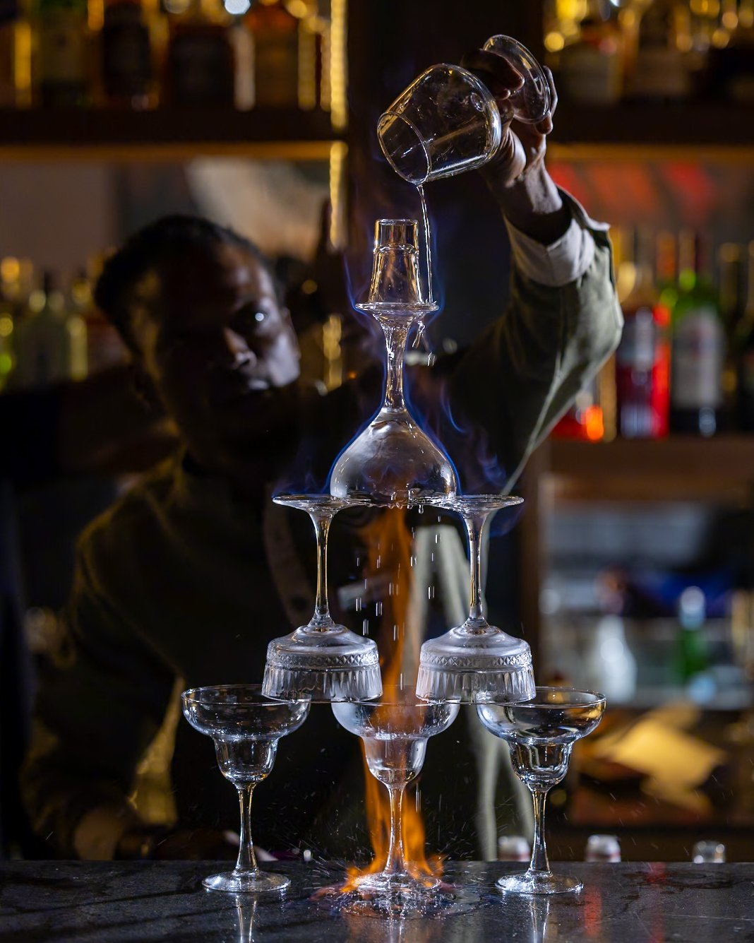 Bartender pouring a flaming cocktail tower at the AYA bar