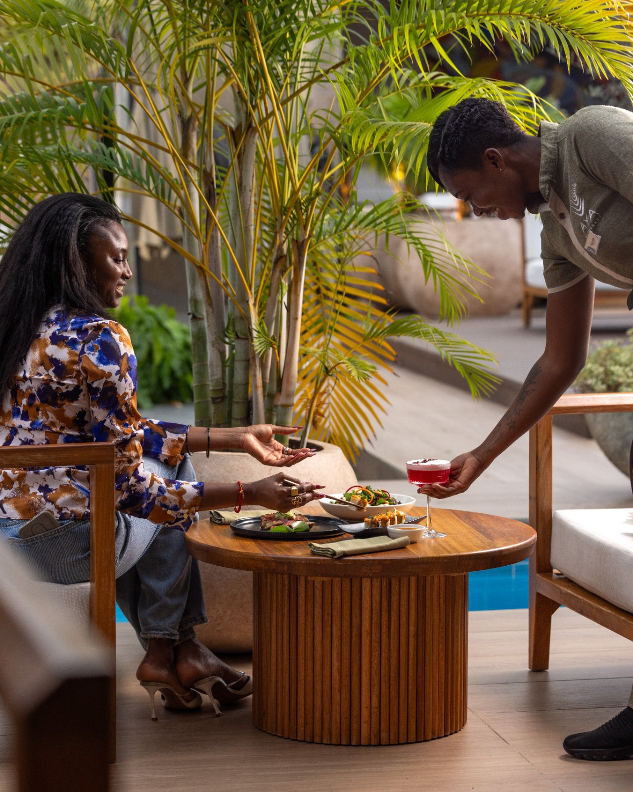 Guests served cocktails and small plates on the poolside terrace at AYA